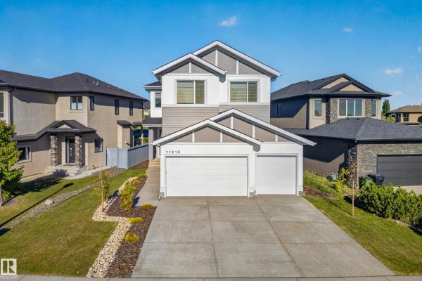 Front exterior view of a two-story house with a gray and white facade, a paved driveway, and a garage. - 11010 174a Av Nw, Edmonton