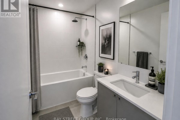 Modern bathroom with a bathtub, white tiled walls, and grey vanity. - 1102 - 10 Oak Street, Toronto