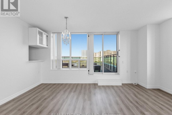 Spacious room with large windows, laminate flooring, and view of the balcony - 1102 - 2800 Warden Avenue, Toronto