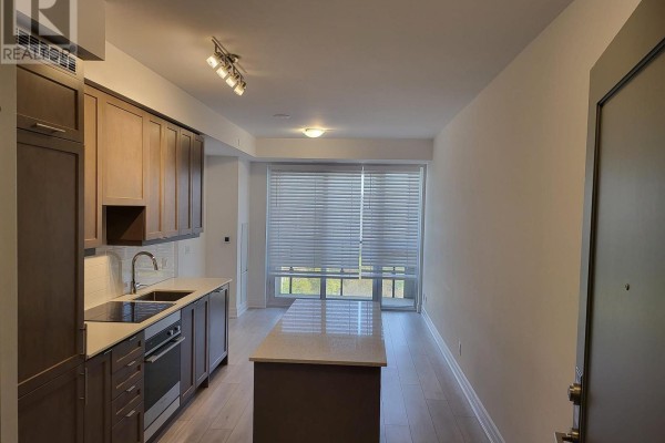 View of a modern kitchen with grey cabinets, stainless steel appliances, and an island. - 1102 - 30 Elm Drive W, Mississauga
