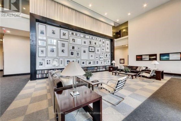 Apartment building lobby with a large framed photo wall, checkered floor, and modern furniture. - 1102 - 438 King Street W, Toronto