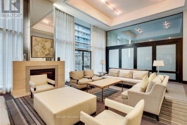 Apartment building lounge area with a fireplace, comfortable seating, and large windows with city views. - 1102 - 438 King Street W, Toronto