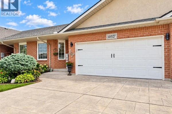 Close-up of the brick facade and white double garage door with black hardware. - 11027 Leathorne, Windsor
