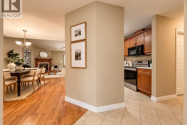 View from a hallway into the dining room, kitchen, and living room with hardwood floors. - 11027 Leathorne, Windsor