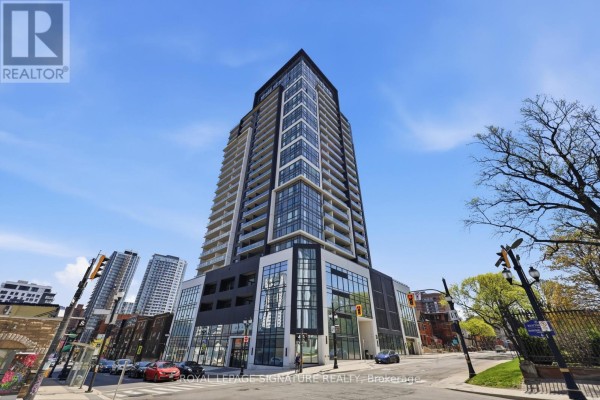 The lobby of the apartment building has white sofas, a dark feature wall, and marble tile floors. - 1103 - 15 Queen Street S, Hamilton
