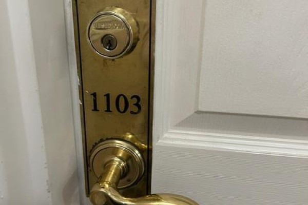 Close-up of the brass doorknob and lock with the number 1103 on the apartment door. - 1103 - 350 Princess Royal Drive, Mississauga