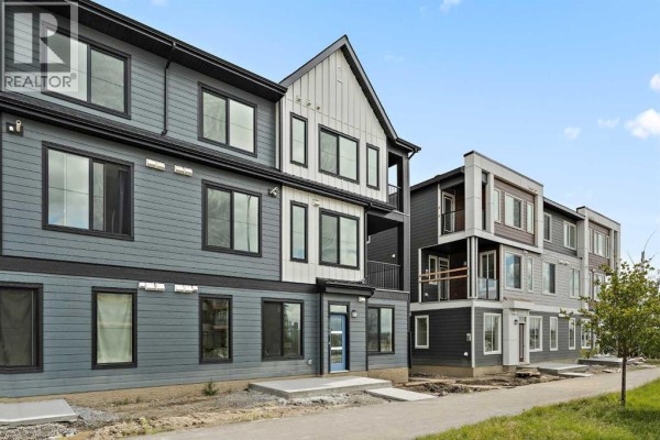 View of a townhouse complex facade with contrasting grey and white siding, black windows, and balconies. - 1104, 60 Howse Lane, Calgary