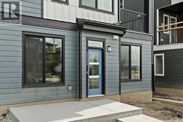 Close-up of a townhouse entrance with a blue door, glass panels, and dark grey horizontal siding. - 1104, 60 Howse Lane, Calgary