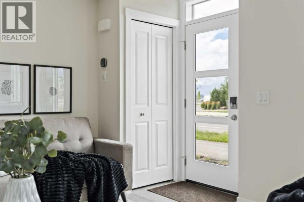 Interior view of a townhouse foyer with a white door, gray sofa, and framed art on the wall. - 1104, 60 Howse Lane, Calgary