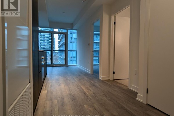 Hallway leading to living spaces, with large windows and modern flooring. - 1104 - 127 Broadway Avenue, Toronto