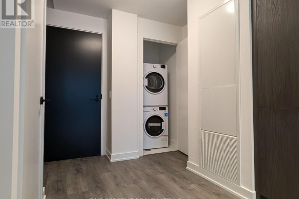 Laundry area with stacked washer and dryer, adjacent to a closet space. - 1104 - 127 Broadway Avenue, Toronto