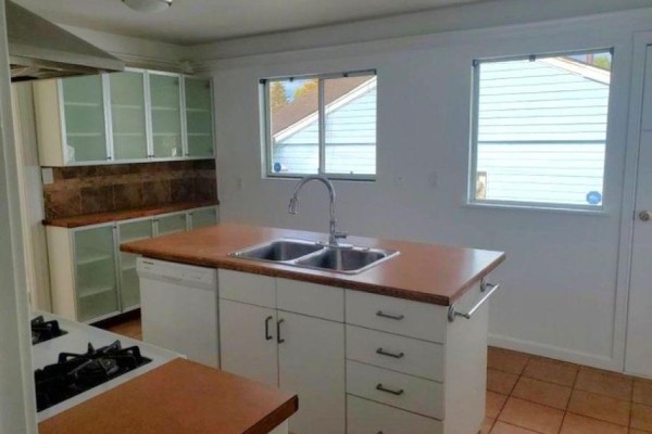 Kitchen with island, stainless steel appliances, and white cabinets. - 11044 Oriole Drive, Surrey