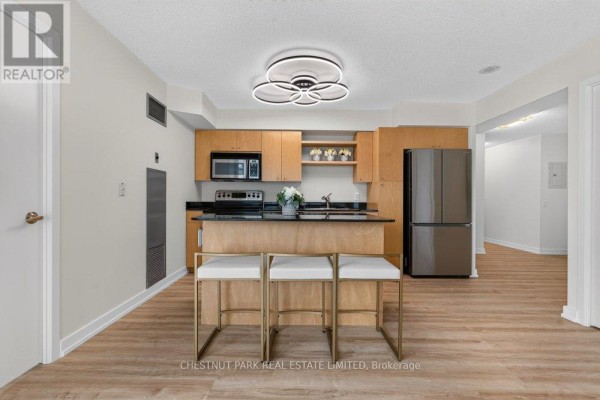 Kitchen with light wood cabinets, black granite countertops, and a central island with seating. - 1105 - 361 Front Street W, Toronto