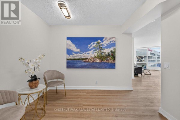 Hallway with a large landscape painting, two accent chairs, and a side table leading to the living area. - 1105 - 361 Front Street W, Toronto
