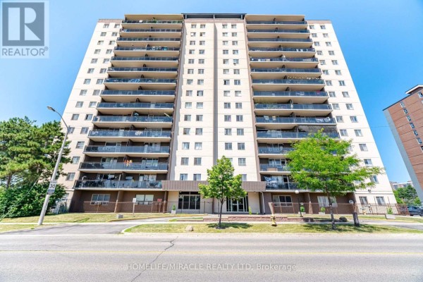 Front facade of a beige apartment building with many balconies and trees in front. - 1105 - 60 Stevenson Road, Toronto