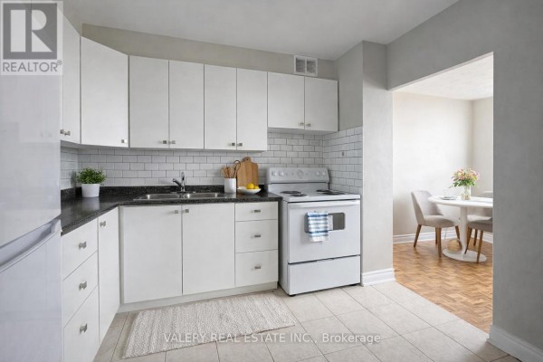White kitchen with subway tile backsplash, dark countertop, and white appliances. - 1105 - 890 Jane Street, Toronto