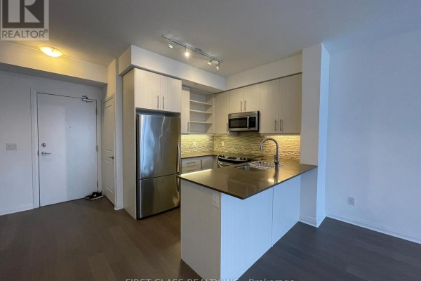 Kitchen and entryway of an apartment with stainless steel appliances and hardwood floors. - 1106 - 55 Oneida Crescent, Richmond Hill