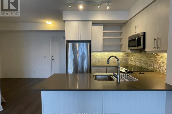 Corner kitchen with stainless steel appliances, island, and view of the living area. - 1106 - 55 Oneida Crescent, Richmond Hill