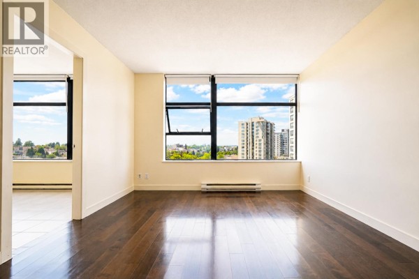 Bright living space with large windows and dark wood floors, overlooking buildings. - 1106 5380 Oben Street, Vancouver