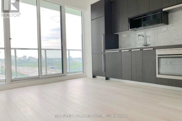 Open concept living area with dark wood cabinets, stainless steel appliances, and large windows. - 1107 - 115 Mcmahon Drive, Toronto