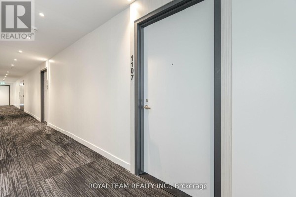 Hallway with white walls, elevator doors, and unit door 1107 on the right. - 1107 - 185 Alberta Avenue, Toronto