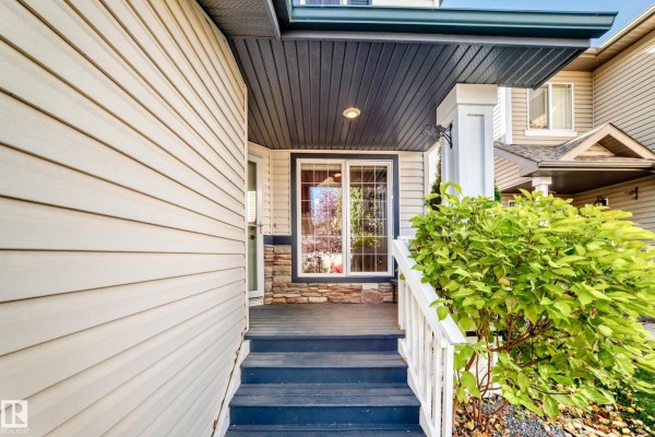 Covered front porch with dark blue steps, white railings, and a sliding glass door. - 1108 117 St Sw, Edmonton