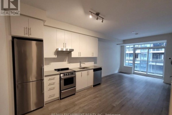 Open kitchen with stainless steel appliances, white cabinetry, and a spacious living area. - 1109 - 212 King William Street, Hamilton