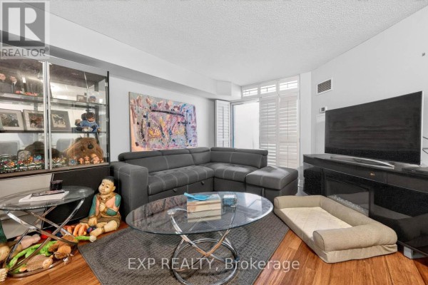A modern living room with a sectional sofa, coffee table, and television. - 1109 - 5 Northtown Way, Toronto