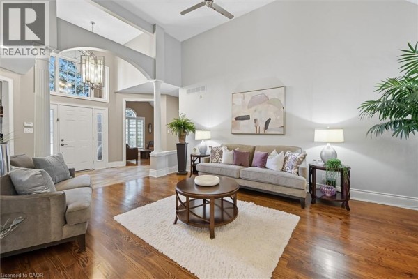 Spacious living room with vaulted ceiling, arched entryway, sofas, and hardwood floors. - 1109 Forestvale Drive, Burlington