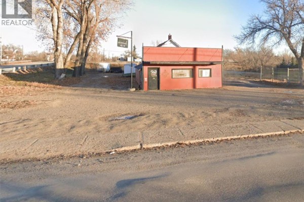 Aerial view of the commercial building with surrounding gravel lot and trees. - 1109 South Railway Street E, Swift Current