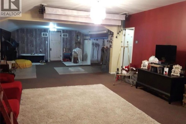 Interior of a commercial space with red walls, brown carpet, and various decor. - 1109 South Railway Street E, Swift Current