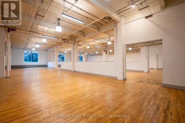Lobby area with concrete floors, exposed brick walls, seating, and a glimpse of a kitchenette. - 110c - 219 Dufferin Street, Toronto