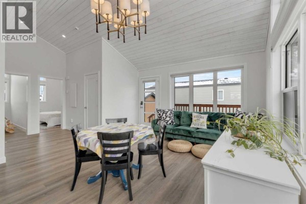 Combined kitchen, dining, and living area with large windows, white cabinets, and a green sofa. - 111, 41310 Range Road 282, Rural Lacombe County