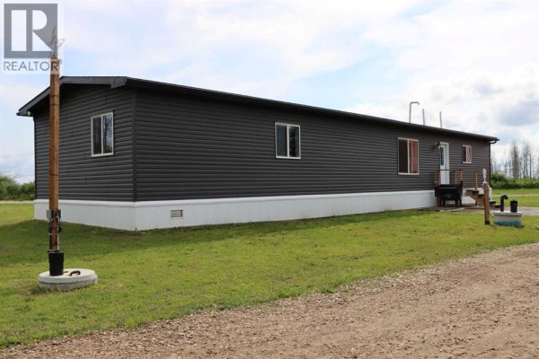 A long shot of the dark grey mobile home's side with multiple windows and a wooden utility pole in front. - 111, 71127 Range Road 234, Rural Greenview No  16, M D  Of