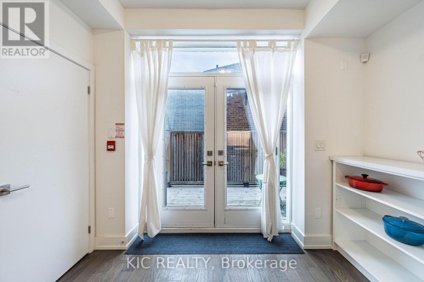 Interior view looking out through glass double doors to a wooden deck and patio furniture. - 111 - 1183 Dufferin Street, Toronto