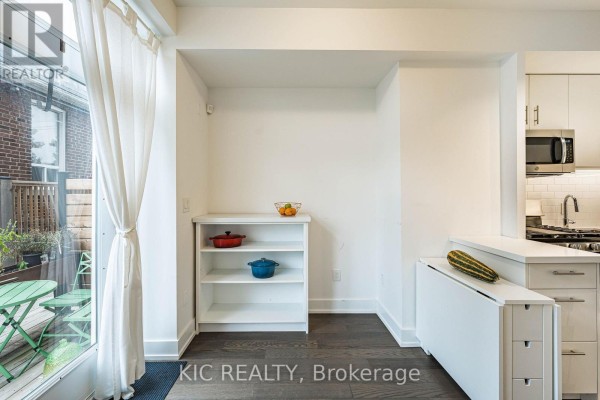 Small dining area with white shelves, a drop-leaf table, and a glimpse of a kitchen. - 111 - 1183 Dufferin Street, Toronto