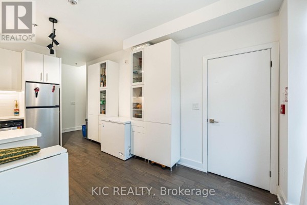 Modern kitchen with stainless steel appliances, white cabinets, and dark hardwood floors. - 111 - 1183 Dufferin Street, Toronto