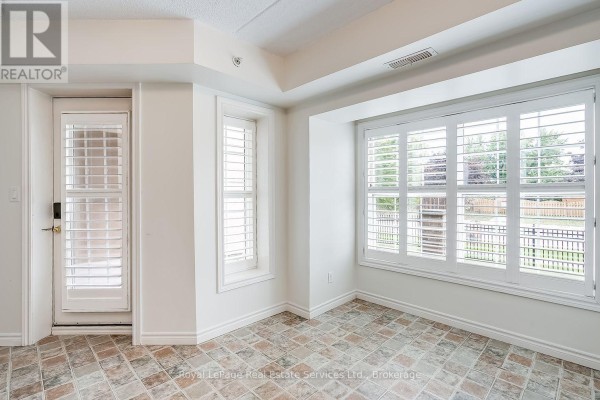 Room with large windows, white shutters, and tiled floor. - 111 - 1460 Bishops Gate, Oakville