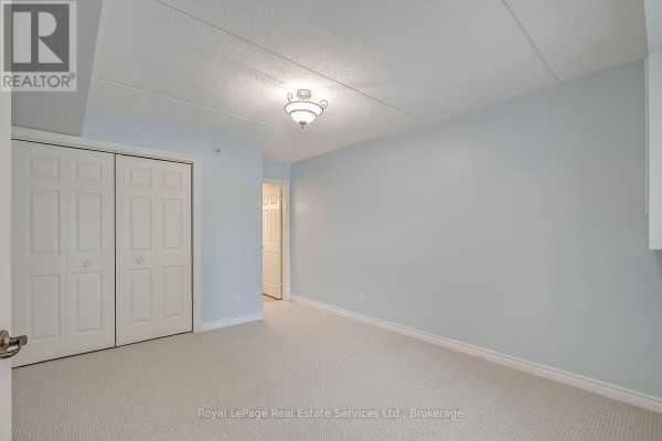 Bedroom with light blue walls, carpet, and double closet doors. - 111 - 1460 Bishops Gate, Oakville