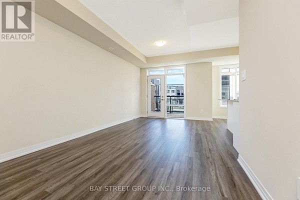 Spacious living room with laminate flooring and access to balcony - 111 - 1573 Rose Way, Milton