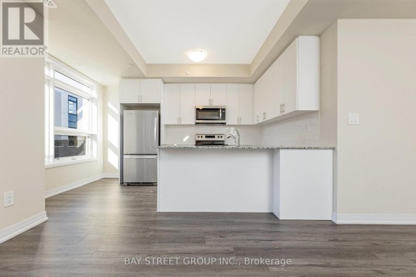 Open kitchen area with stainless steel appliances and white cabinetry - 111 - 1573 Rose Way, Milton
