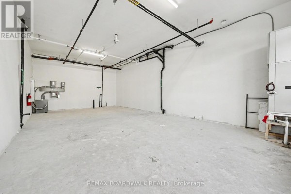 Interior view of an empty, unfinished commercial space with concrete floors and exposed pipes. - 111 - 2370 Tenth Line Road, Ottawa