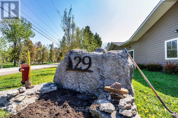 A large rock with the number 29 on it, set in a garden area with a shovel. - 111 - 29 Lakewood Crescent, Kawartha Lakes