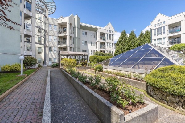 Courtyard pathway with flower beds and apartment building exterior - 111 2575 Ware Street, Abbotsford