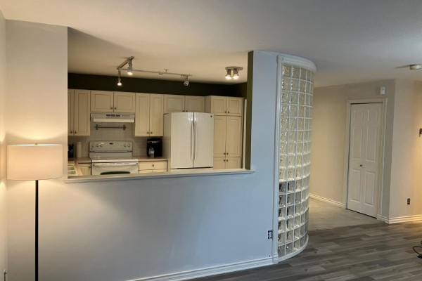 Open concept kitchen with white cabinets and appliances, view of glass block wall - 111 2575 Ware Street, Abbotsford