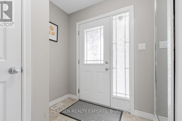 Interior entryway with a white door, frosted glass sidelight, beige walls, and a dark patterned rug. - 111 John Brabson Crescent, Guelph