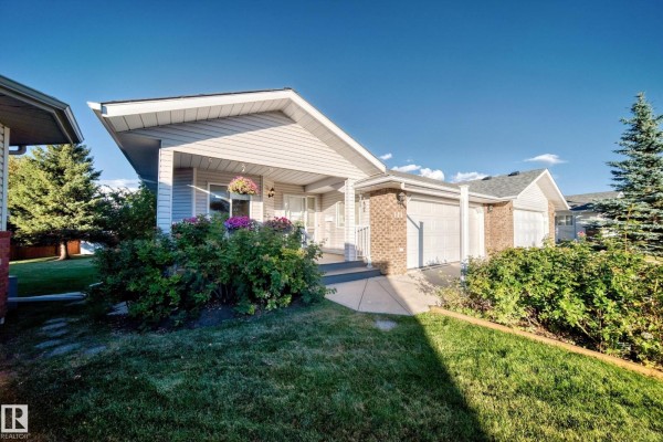 Exterior view of the duplex showing the front entrance, garage doors, and surrounding landscaping. - 111 Lakeside Pl, Leduc