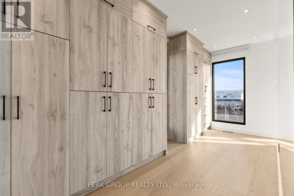 Modern hallway with floating wood and glass staircase, large windows, and art. 111 Millpond Road Niagara On The Lake