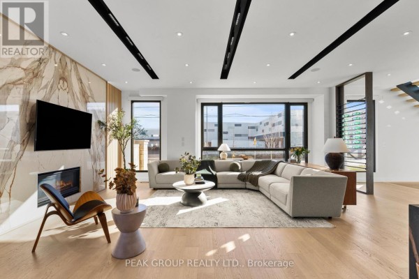 Modern living room with fireplace, sectional sofa, and large windows - 111 Millpond Road Niagara On The Lake