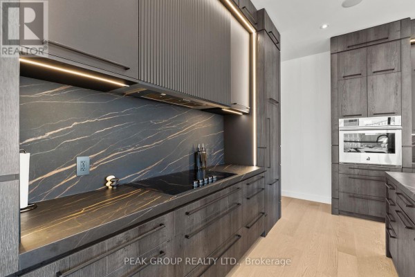 Modern kitchen with dark wood cabinets, marble backsplash & built-in oven - 111 Millpond Road Niagara On The Lake